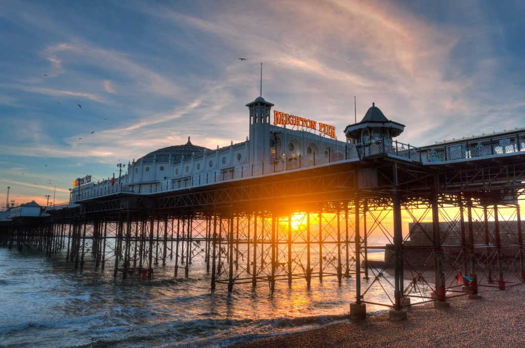 Sunset view of Brighton Pier with its iconic architecture against the vibrant sky and ocean.